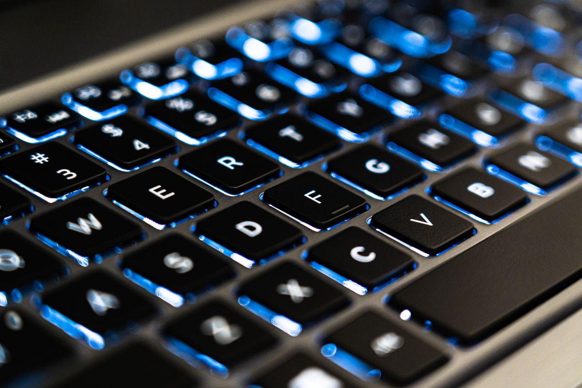 A close-up of a blue backlit laptop keyboard