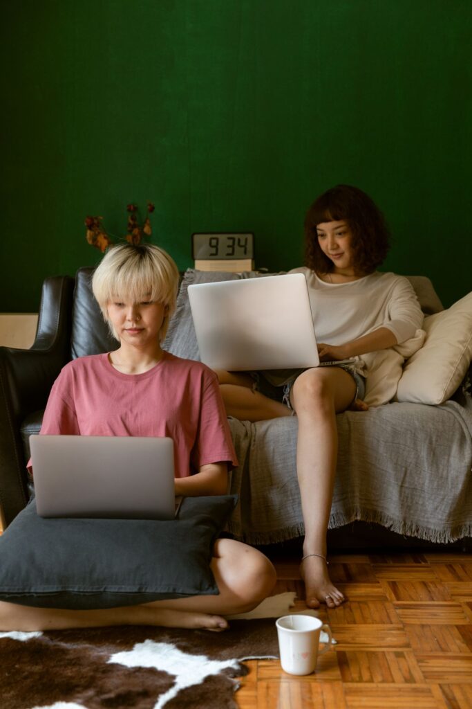 Two people working from home on laptops in a cozy living room with a green wall